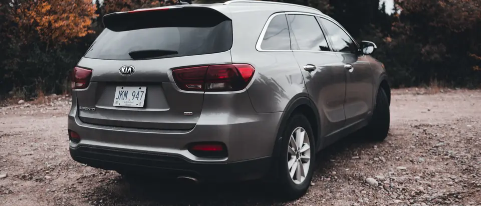 Rear glass of a grey SUV parked on a gravel road